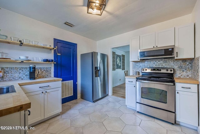 kitchen with white cabinetry, sink, backsplash, light tile patterned floors, and appliances with stainless steel finishes