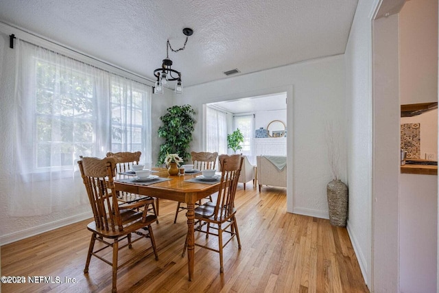 dining room featuring light hardwood / wood-style floors and a textured ceiling