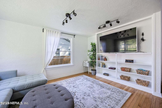 living room with rail lighting, light hardwood / wood-style floors, and a textured ceiling