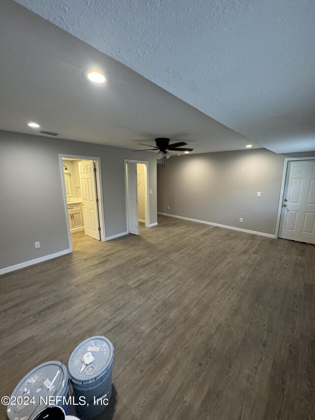 unfurnished living room featuring ceiling fan, a textured ceiling, and dark hardwood / wood-style flooring