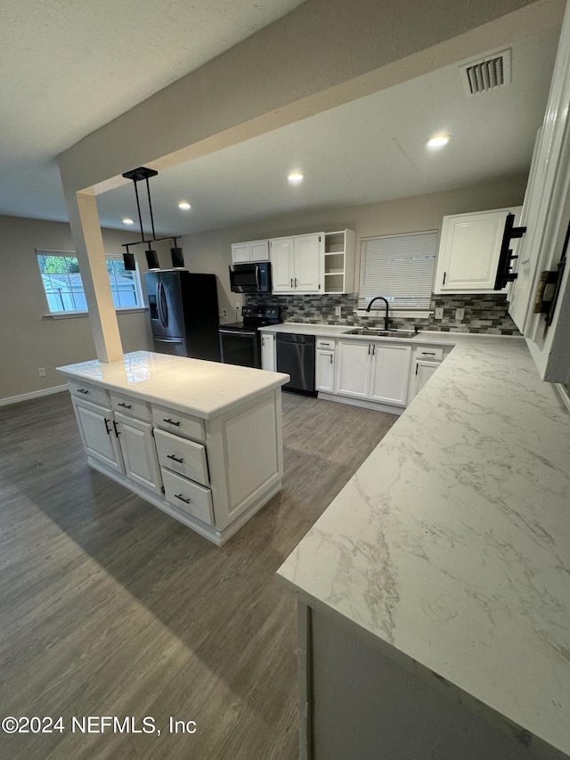 kitchen featuring pendant lighting, sink, a kitchen island, white cabinetry, and black appliances