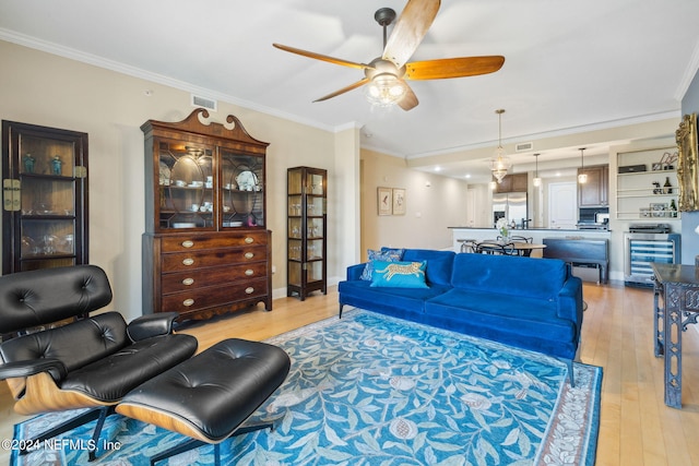 living room featuring light hardwood / wood-style floors, ceiling fan, and crown molding