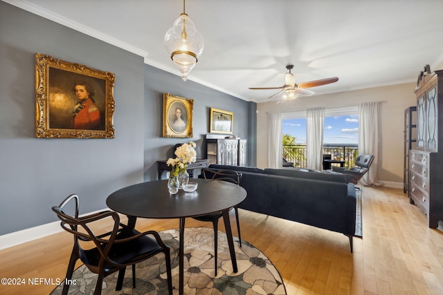 dining area featuring ceiling fan, a fireplace, ornamental molding, and light wood-type flooring