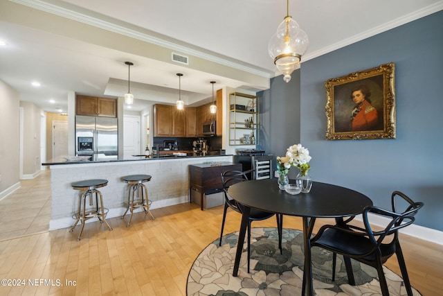 dining room featuring sink, crown molding, and light hardwood / wood-style flooring