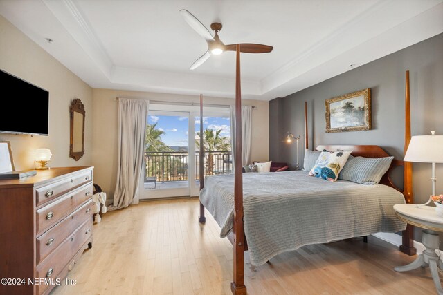 bedroom with ceiling fan, light wood-type flooring, access to outside, and a tray ceiling