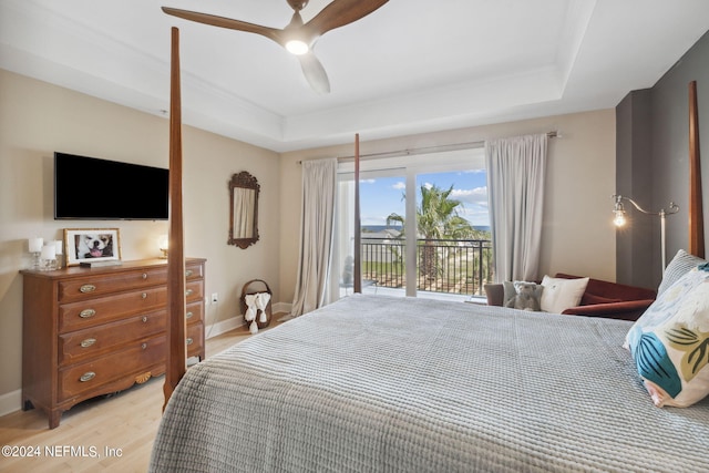 bedroom with access to outside, ceiling fan, light hardwood / wood-style flooring, and a tray ceiling