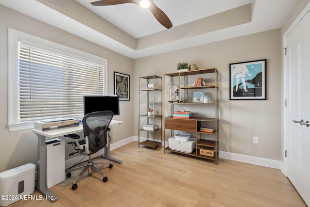 office space featuring light wood-type flooring, a raised ceiling, and ceiling fan