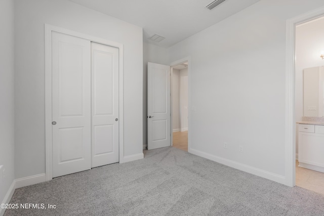 unfurnished bedroom featuring light colored carpet, connected bathroom, and a closet