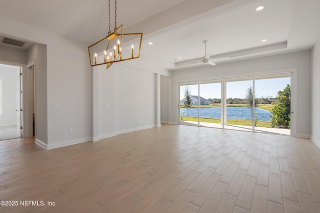 spare room with ceiling fan with notable chandelier and a water view