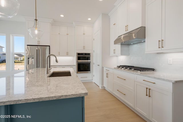 kitchen with white cabinets, sink, an island with sink, decorative light fixtures, and stainless steel appliances