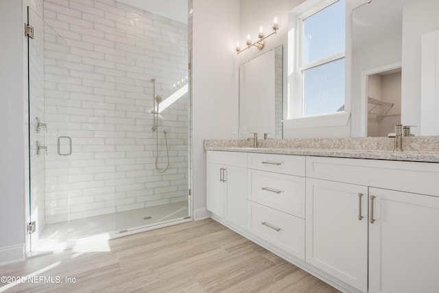 bathroom featuring a shower with door, vanity, and hardwood / wood-style flooring