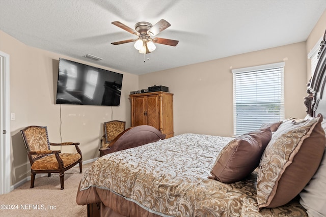 carpeted bedroom with ceiling fan and a textured ceiling