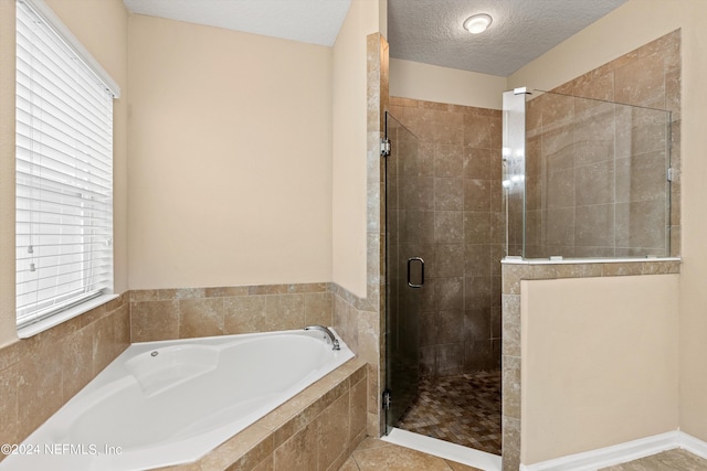 bathroom with a textured ceiling, separate shower and tub, and tile patterned floors