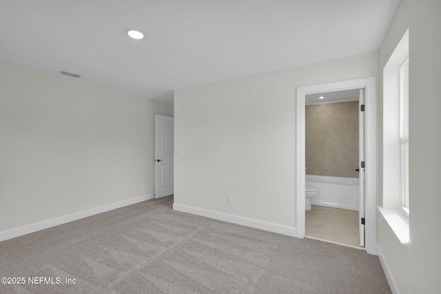 unfurnished bedroom with light colored carpet and ensuite bathroom