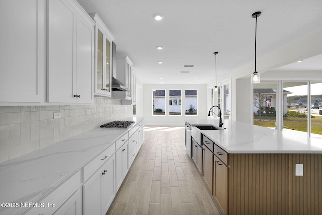 kitchen with hanging light fixtures, white cabinets, light stone counters, and a spacious island