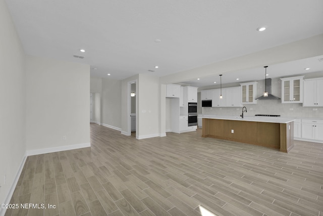 kitchen with a large island, white cabinetry, hanging light fixtures, tasteful backsplash, and wall chimney exhaust hood