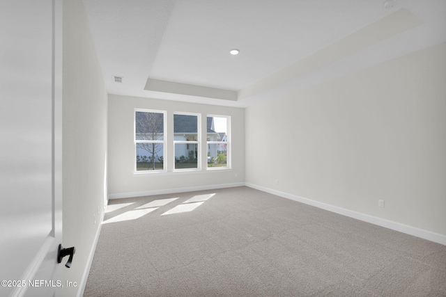 empty room with a tray ceiling and carpet flooring