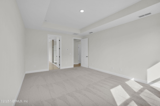 empty room featuring light colored carpet and a tray ceiling