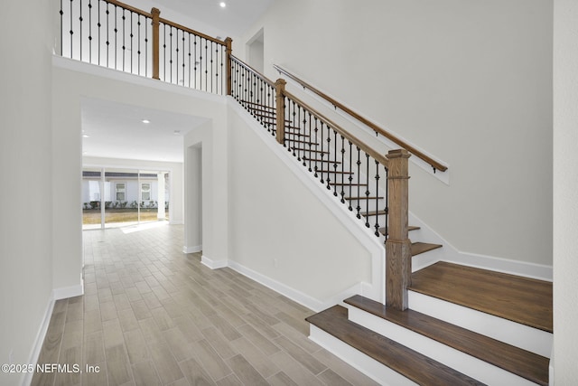 stairs featuring hardwood / wood-style flooring and a towering ceiling