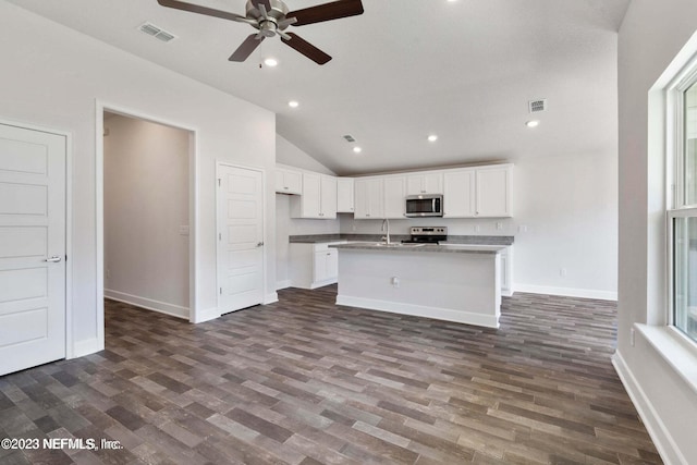 kitchen with dark wood-type flooring, an island with sink, white cabinetry, appliances with stainless steel finishes, and ceiling fan