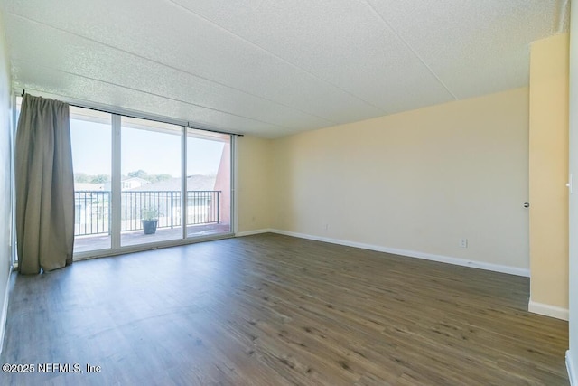 unfurnished room featuring floor to ceiling windows and dark wood-type flooring