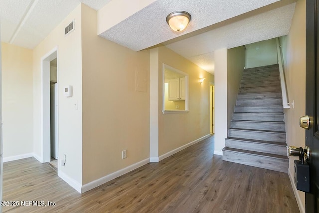 staircase featuring hardwood / wood-style flooring and a textured ceiling