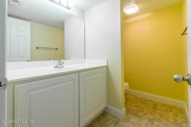 bathroom with a textured ceiling, tile patterned floors, vanity, and toilet