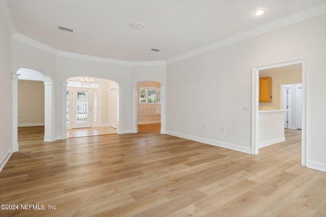 empty room with light wood-type flooring, decorative columns, and crown molding