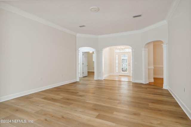 empty room featuring decorative columns, ornamental molding, and light hardwood / wood-style flooring