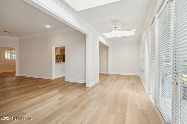 empty room featuring ornamental molding, light wood-type flooring, ceiling fan, and a healthy amount of sunlight