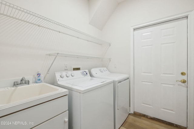 clothes washing area with light hardwood / wood-style flooring, sink, and washing machine and dryer