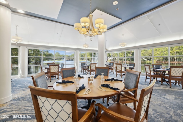 sunroom with lofted ceiling, a water view, and a chandelier