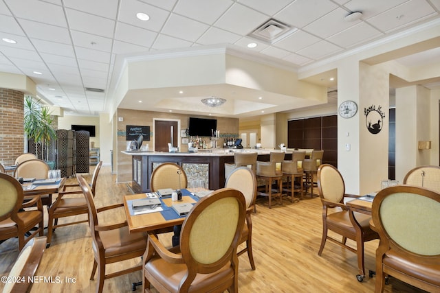 dining area with light wood-type flooring, crown molding, and a drop ceiling