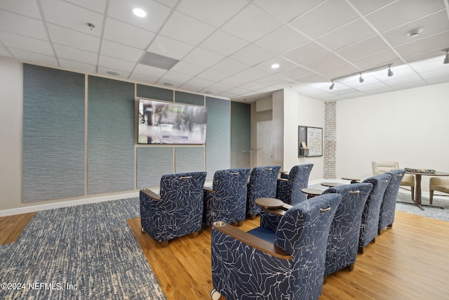 cinema room with a drop ceiling and wood-type flooring