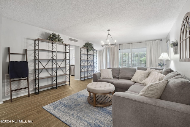 living room featuring hardwood / wood-style flooring, a notable chandelier, and a textured ceiling