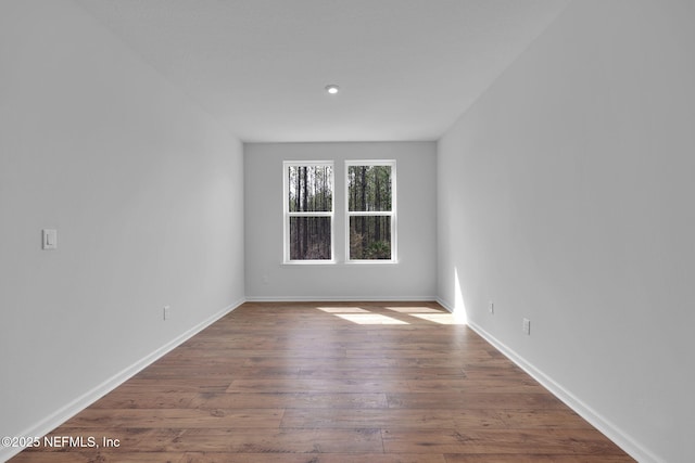 spare room featuring wood-type flooring and baseboards