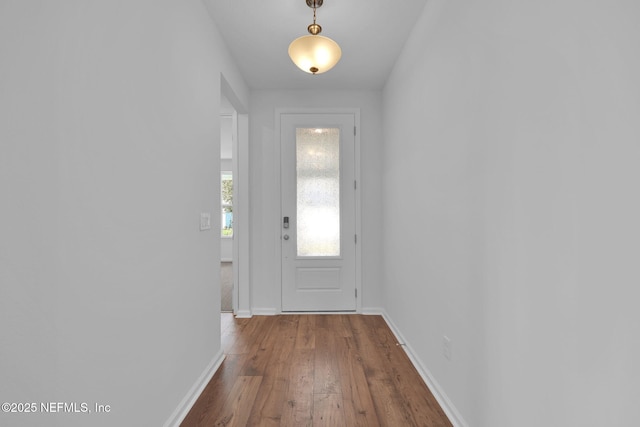 doorway with wood-type flooring and baseboards