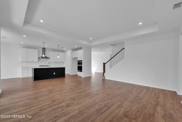 unfurnished living room featuring stairs, dark wood-type flooring, visible vents, and recessed lighting