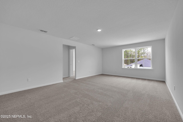 carpeted spare room featuring visible vents, a textured ceiling, and baseboards