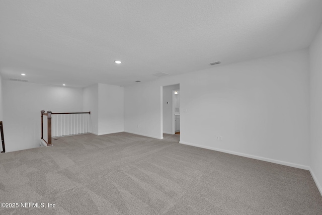 spare room with baseboards, visible vents, light colored carpet, a textured ceiling, and recessed lighting