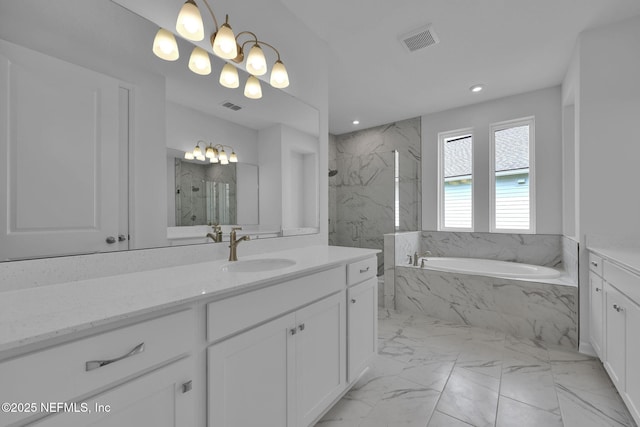 bathroom with marble finish floor, vanity, a garden tub, and visible vents