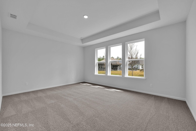 empty room featuring baseboards, visible vents, a raised ceiling, and carpet flooring