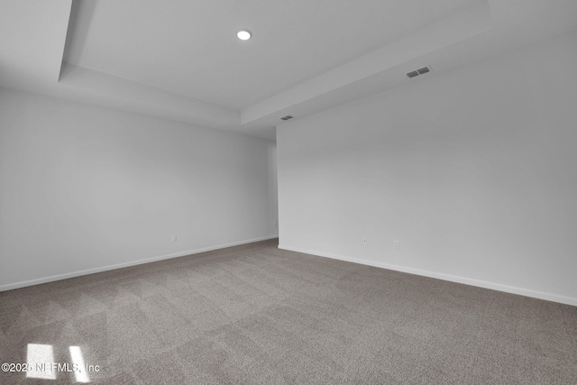 spare room featuring carpet, visible vents, and baseboards