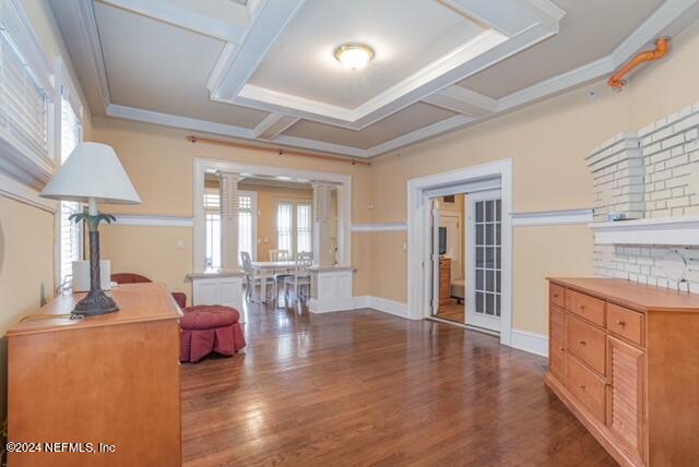 interior space featuring decorative columns, ornamental molding, and dark hardwood / wood-style flooring