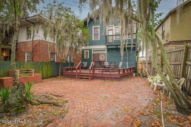 rear view of property featuring a balcony and a deck