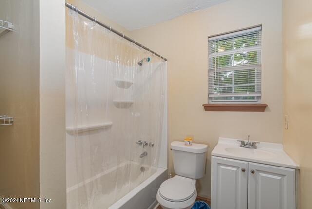 full bathroom with shower / bath combination with curtain, vanity, and toilet