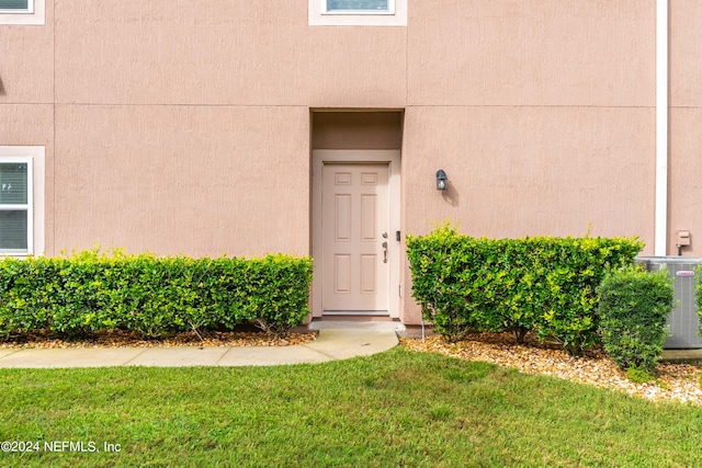 doorway to property with a yard and central AC