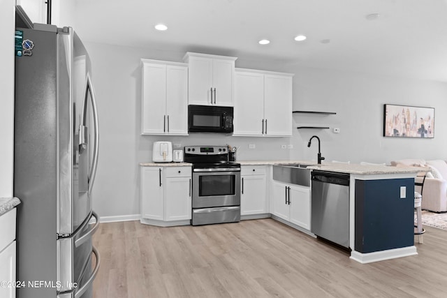 kitchen with stainless steel appliances, white cabinetry, light hardwood / wood-style floors, and sink