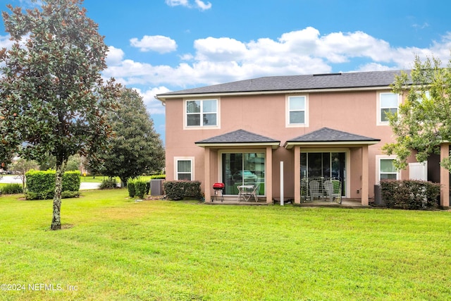 rear view of property featuring cooling unit and a lawn