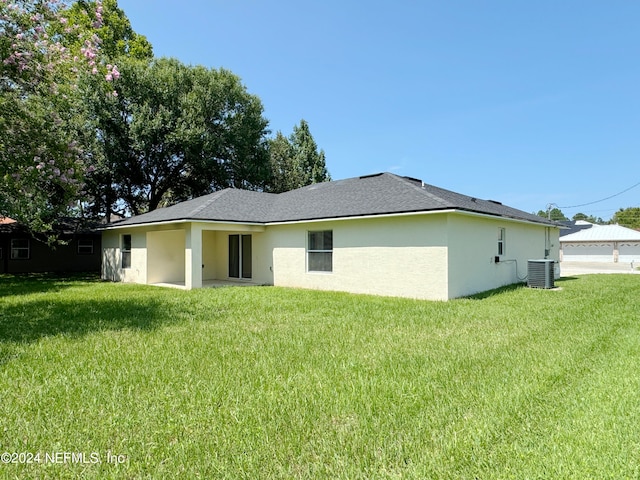 rear view of property featuring a yard and central AC